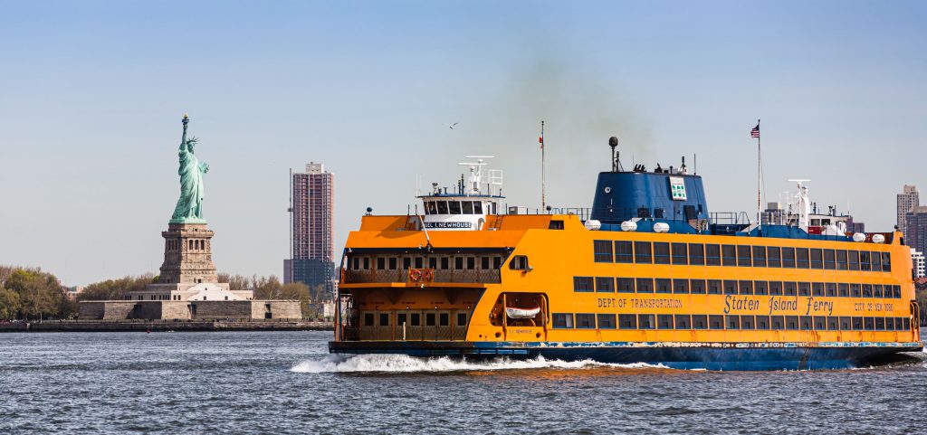 NEW YORK, USA - Apr 28, 2016: Staten Island Ferry passing Statue of Liberty in New York Harbor. Staten Island Ferry is a passenger ferry service operated by New York City Department of Transportation