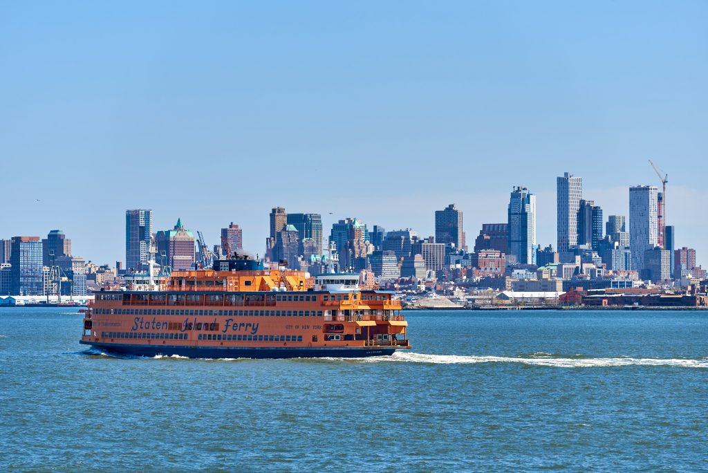 New York, NY - April 6, 2021: A Staten Island Ferry Boat moves north toward the Manhattan Terminal. Behind the boat are the skyscrapers of Downtown Brooklyn