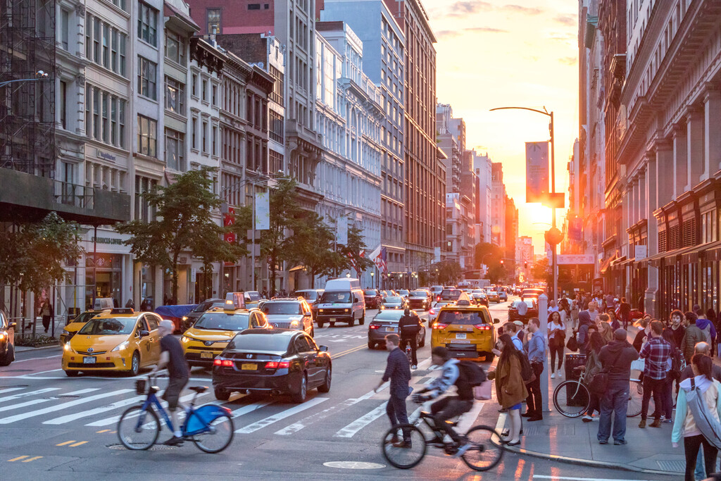 NEW YORK CITY - JUNE 7, 2018: The intersection of 23rd Street and Broadway is busy with people and cars while the sunsets in the background horizon of the Manhattan skyline.