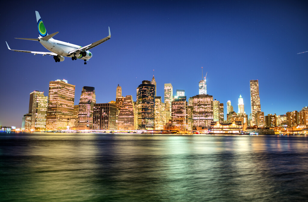 Airplane landing in New York at night. Manhattan skyline on background.