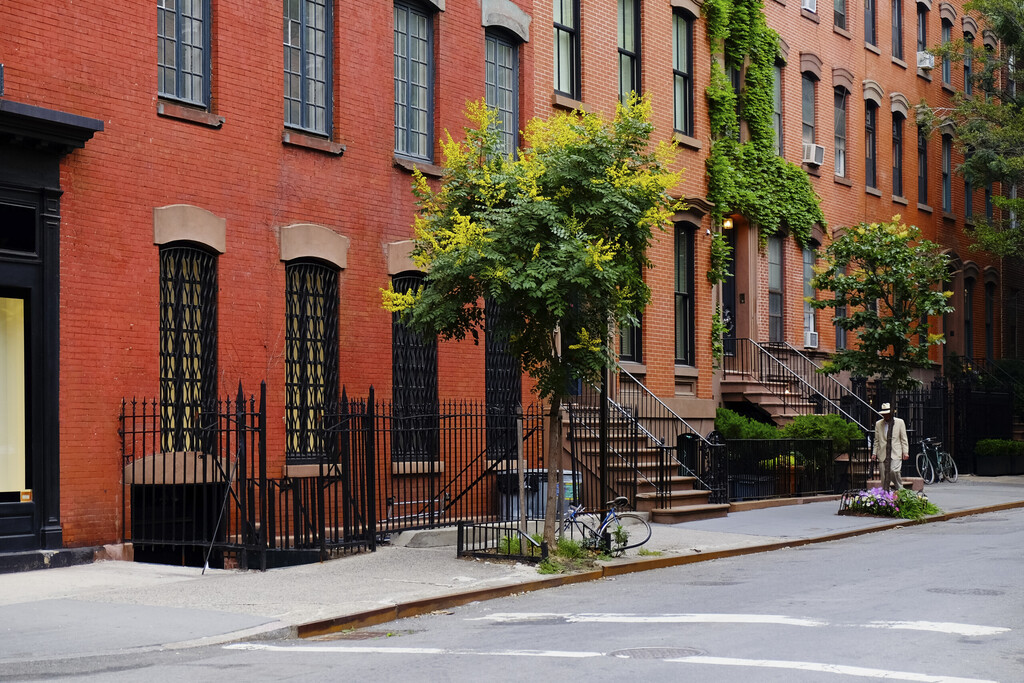 Beautiful buildings in Greenwich Village, Soho district. Entrance doors with stairs and trees, Manhattan New York. Classic red brick apartment building in New York City. Beautiful american street.
