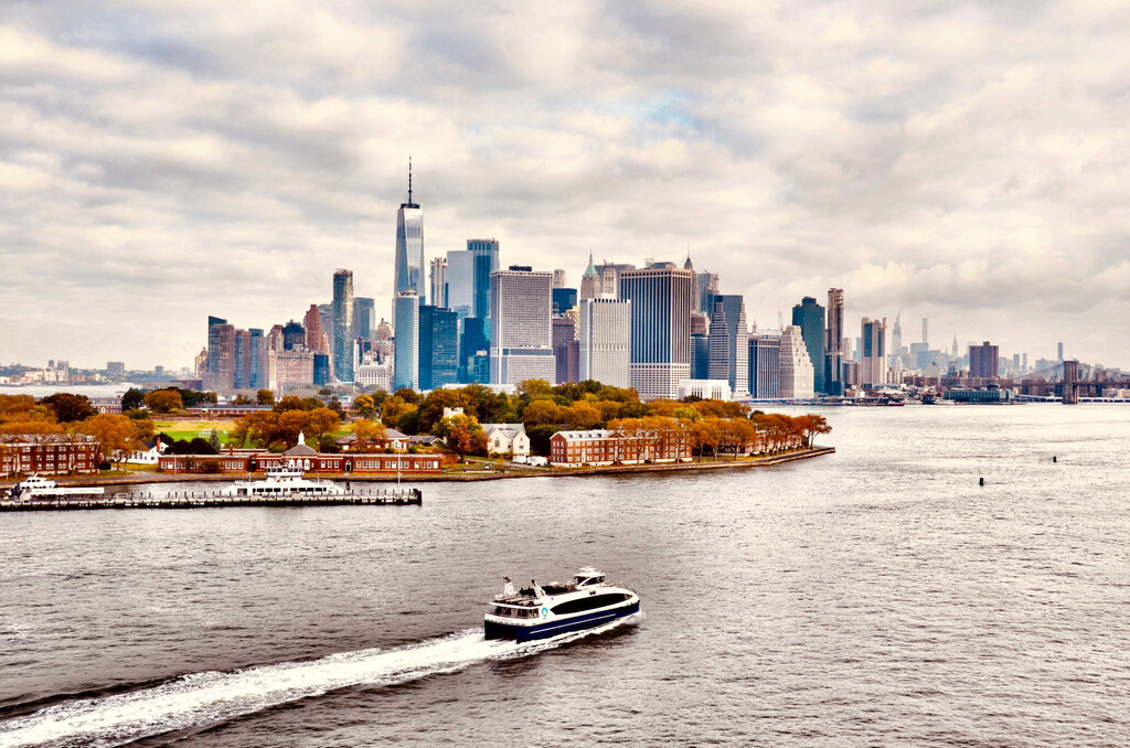 Panoramic and aerial view of downtown Manhattan Skyline and Hudson River. Morning scene after rain, with most cloudy sky. NYC Boat Tours and Sightseeing Cruise sailing in the river 