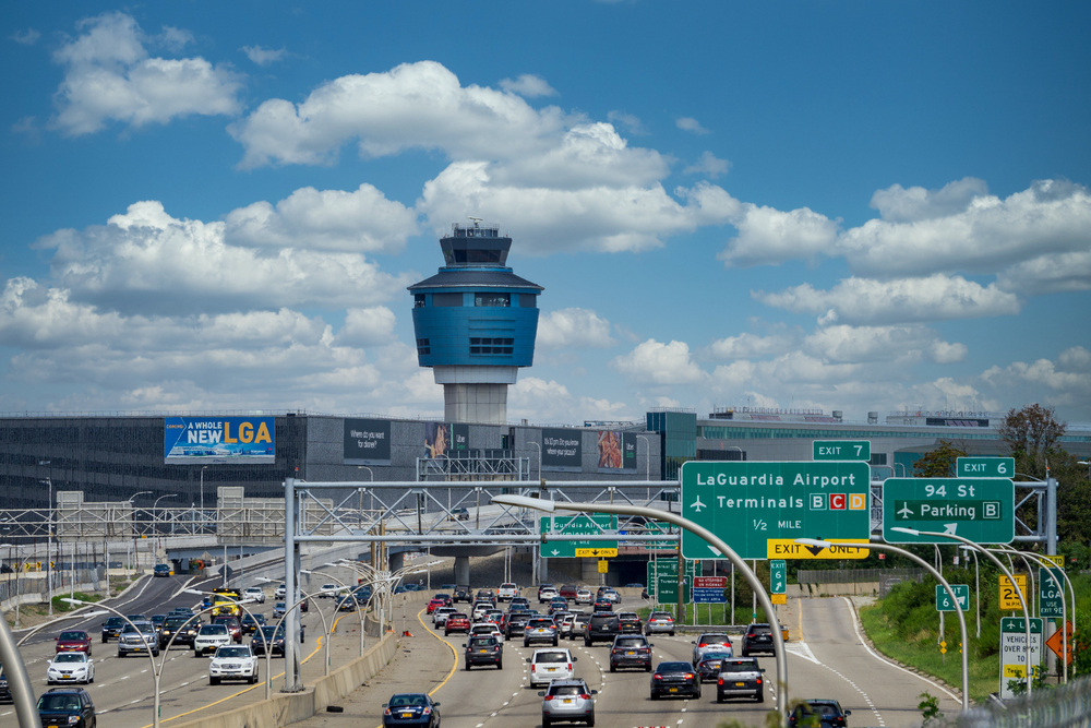 New York, NY / USA - August 15 2020: Traffic car on the highway going to LaGuardia Airport. Air traffic Control Tower seen above terminals