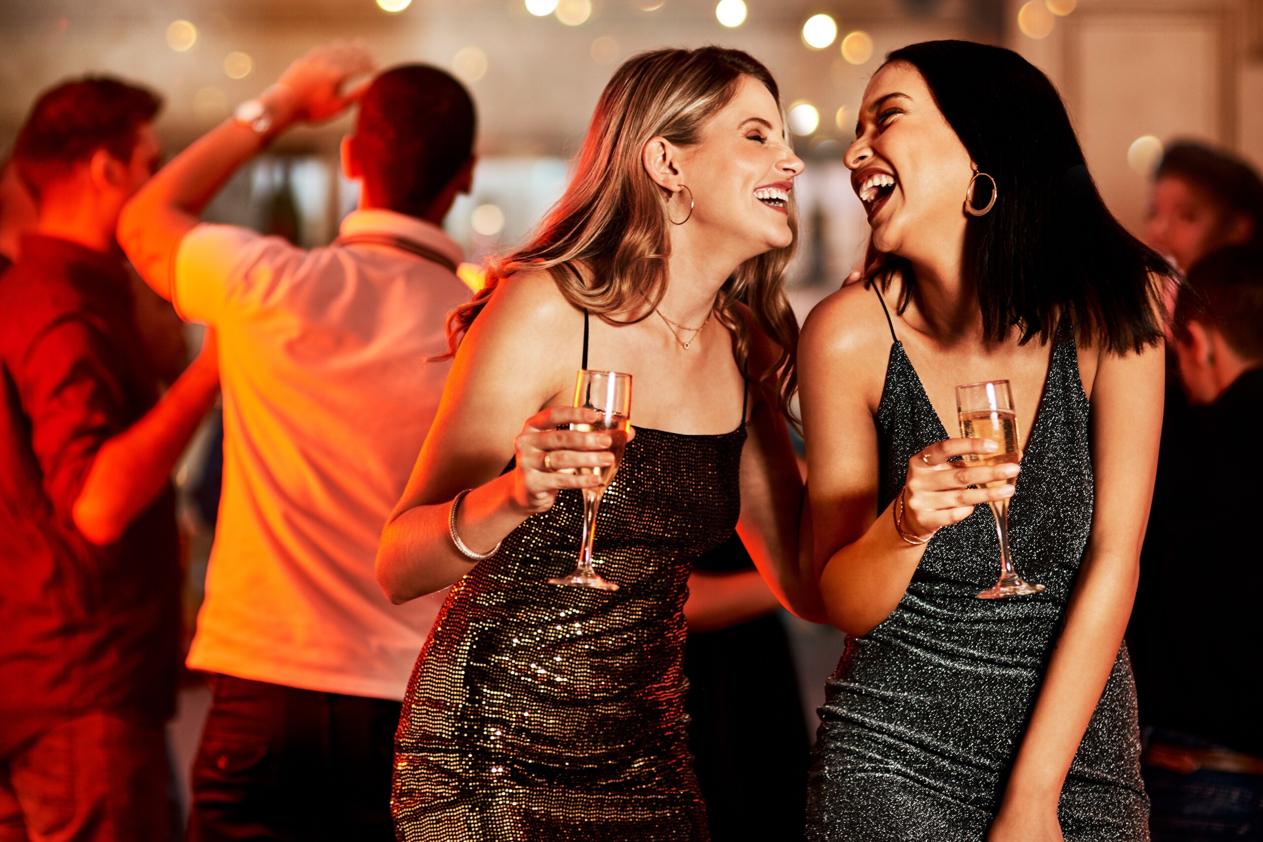 Kobiety śmiejące się podczas wieczornej imprezy szampańskiej, imprezy klubowej lub obchodów urodzin w Nowym Jorku. Uśmiech, szczęśliwi ludzie lub przyjaciele z kieliszkami alkoholu w luksusowej restauracji lub na parkiecie dyskotekowym, licencja: shutterstock/By PeopleImages-Yuri+A